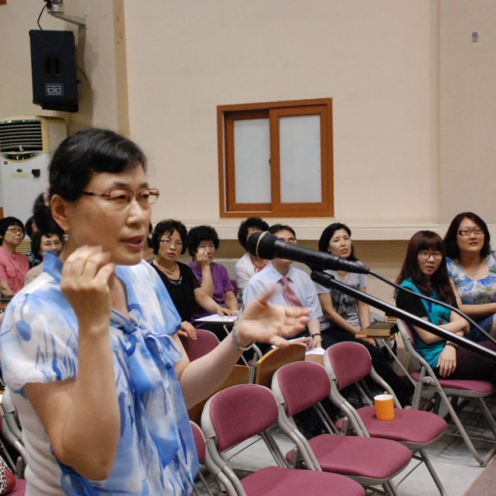 어른 여름성경학교에서 한 성도가 마이크 앞에서 질문하고 청중이 듣는 모습
